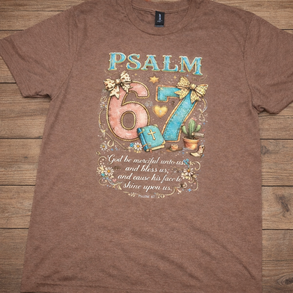 "Psalm 67 God Be Merciful Unto Us Christian t-shirt in Cocoa Mist — colorful whimsical western-inspired graphic with bows, Bible, and Psalm 67:1 verse by Pressed in Faith by Anna"
