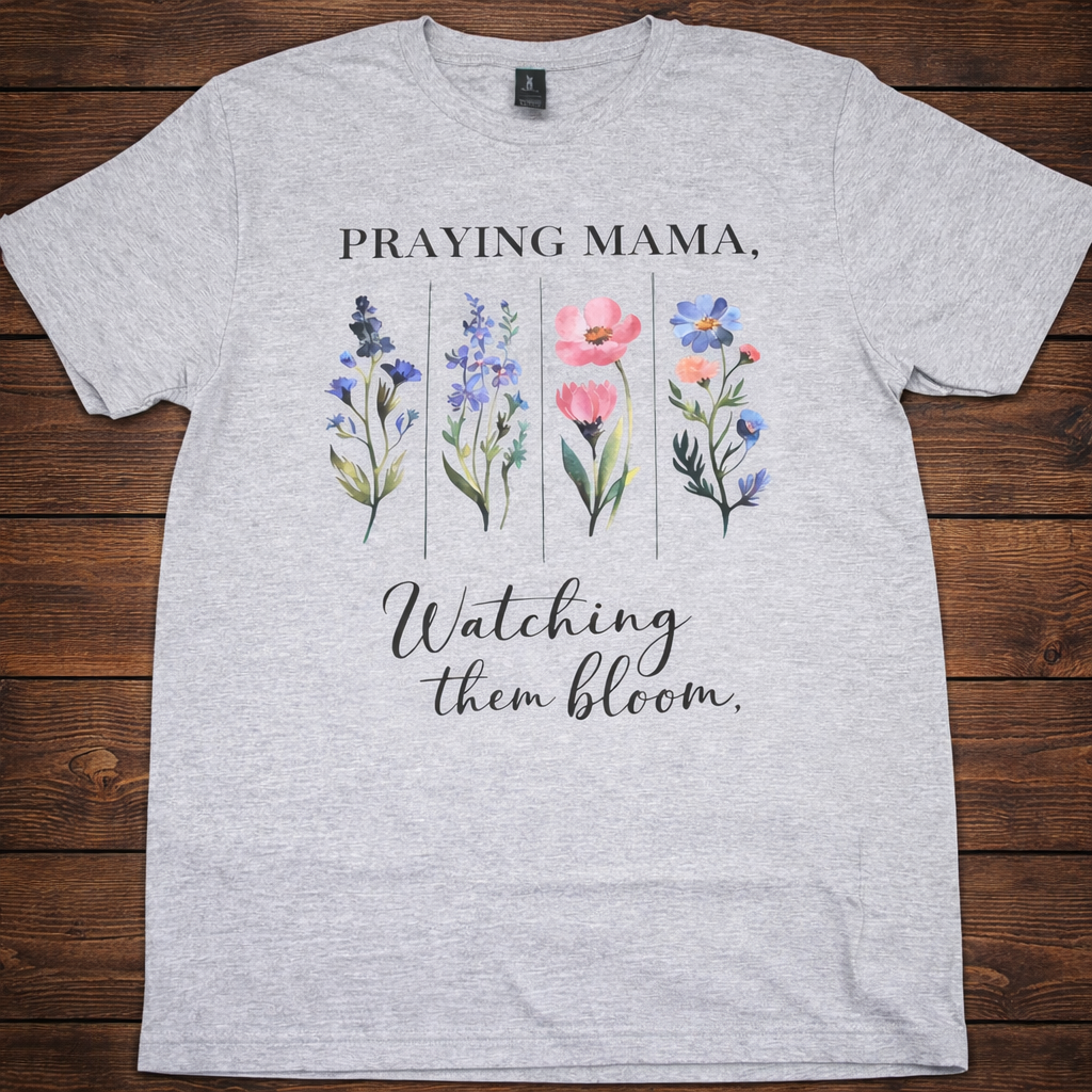 "Praying Mama Watching Them Bloom Christian t-shirt in Sport Grey — watercolor wildflower graphic with lavender, pink, and blue blooms and elegant script 