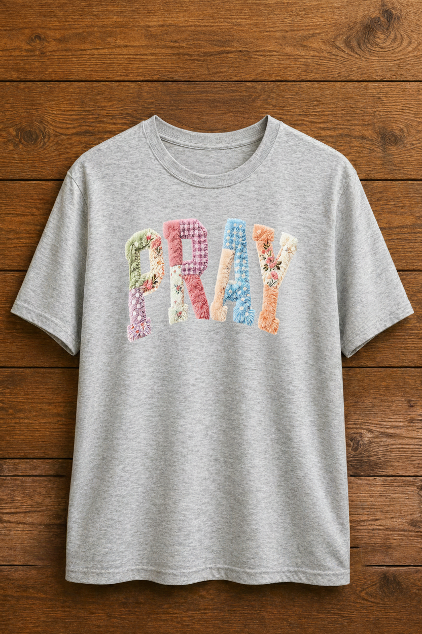 Sport Gray t-shirt with colorful 'PRAY' text on a wooden surface